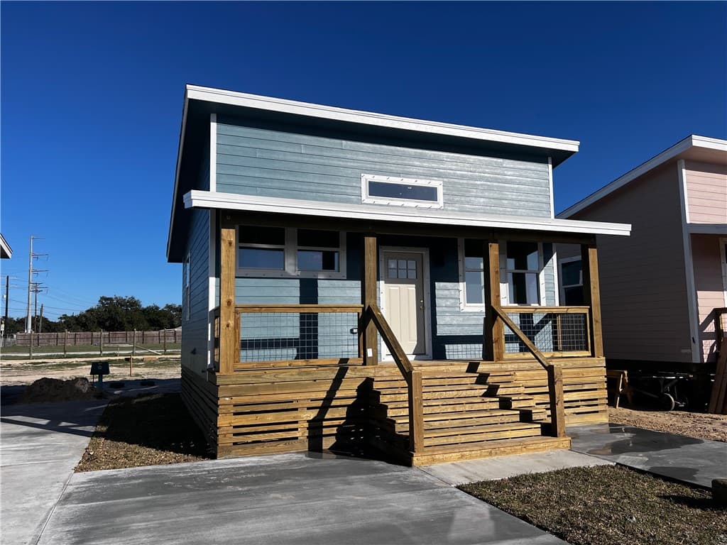 Blue cottage with a porch beside other cottages in the community